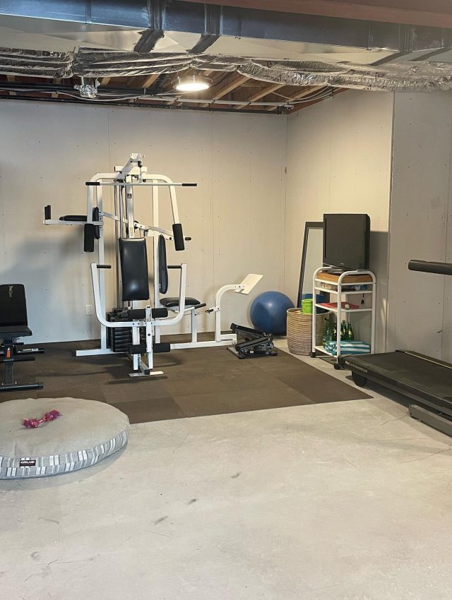 Home Gym After - With the shelving reoriented to create a barrier to the rest of the storage items, we created an open, inviting and functional workout space for all to enjoy.